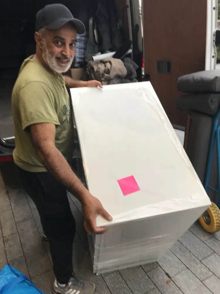 Ali carrying a protected cabinet to the van