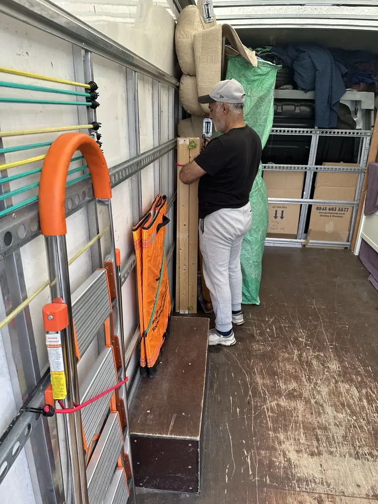 Team securing wrapped furniture inside the Luton van