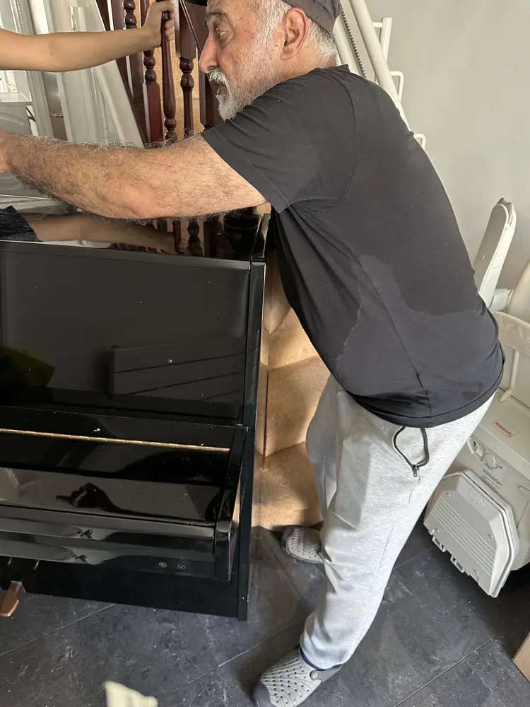 Ali manoeuvring an upright piano