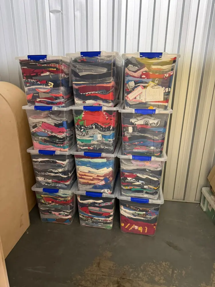 Twelve labelled storage crates stacked in a self-storage unit