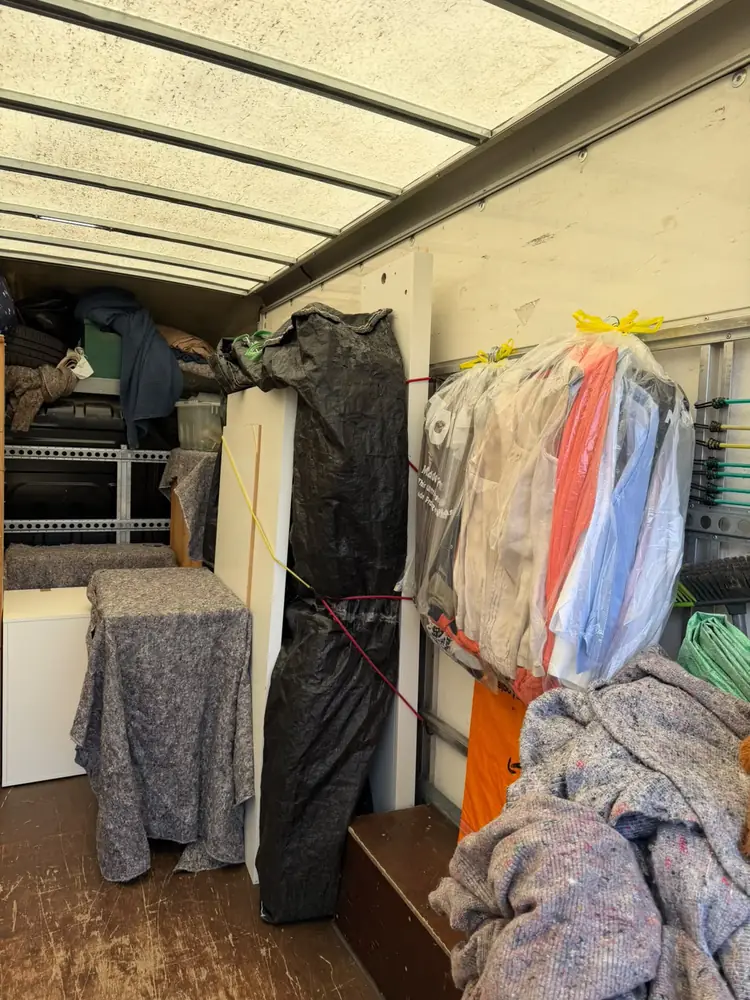 Clothes moved on hangers in garment bags inside the van